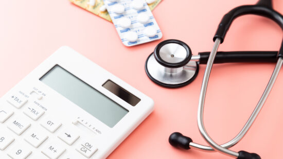 Stethoscope, calculator and pills on pink background.